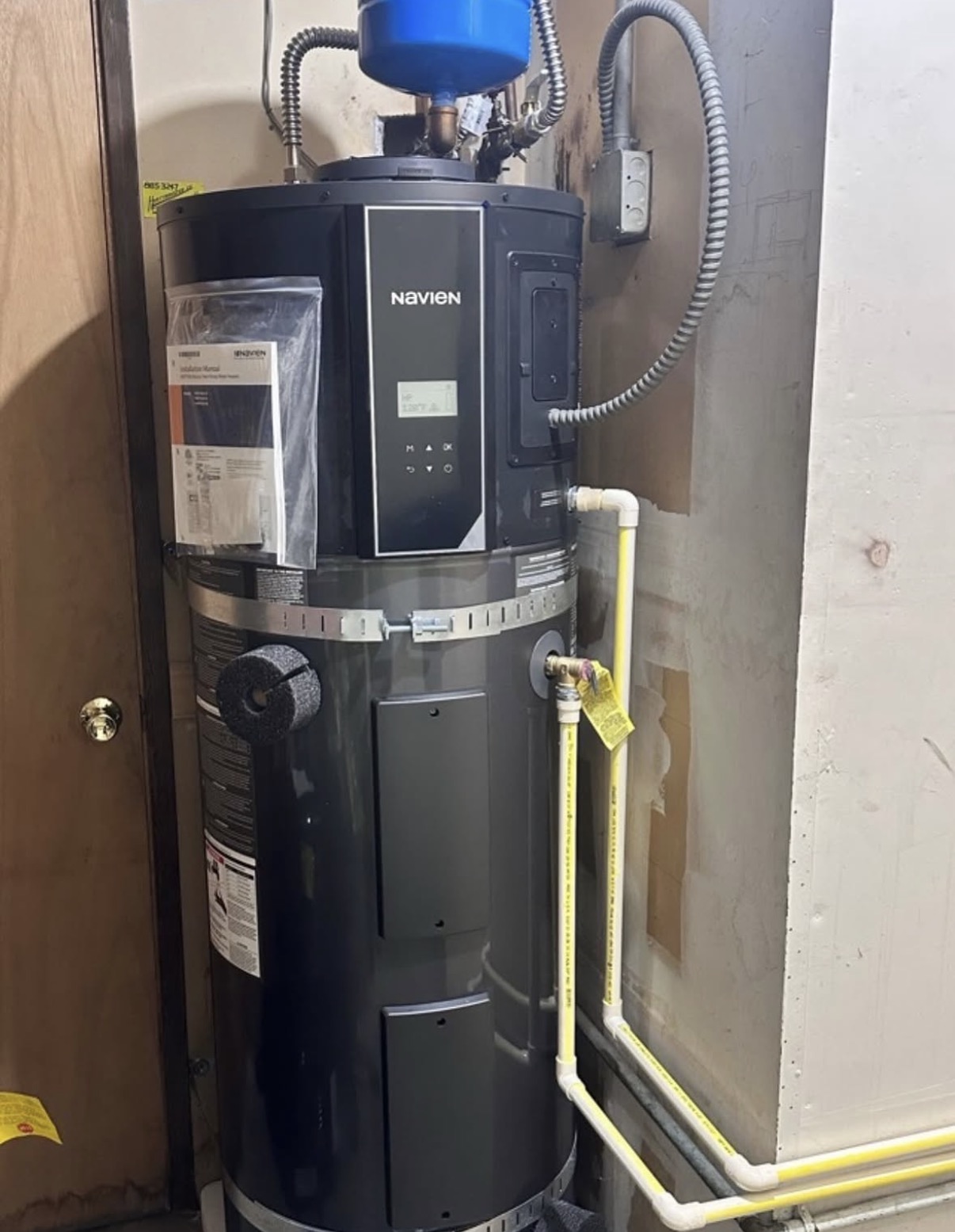 Navien hybrid heat pump water heater installed in a tight Eastside closet with seismic strapping and gas-yellow condensate and supply lines